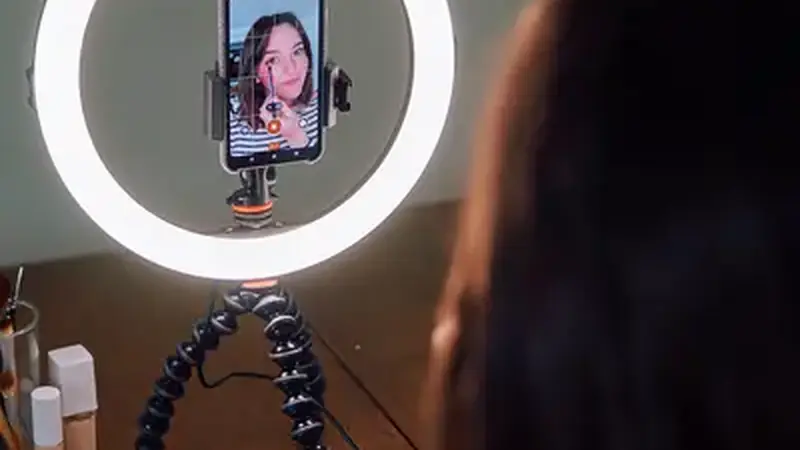 Content creator filming a video with a ring light and smartphone